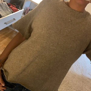 Beige stickad kortärmad tröja - Mysig beige stickad tröja med korta ärmar och rund halsringning. 