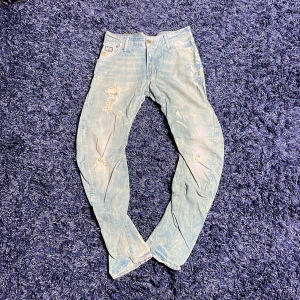 Ljusblå slitna jeans från G-Star - Säljer ett par ljusblå jeans från G-Star med slitna detaljer och distressed look. Modellen är Arc 3D Tapered, vilket ger en snygg tapered passform. Klassisk femficksdesign och läderpatch med logga bak i midjan. Hör av er vid minsta fundering🙌