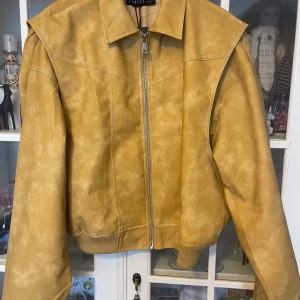 Beige bomberjacka från Lioness - Säljer en beige bomberjacka från Lioness med dragkedja framtill och klassisk krage. Jackan har en oversized passform och är gjord i ett mockaliknande material. Perfekt för dig som vill ha en trendig och stilren look.