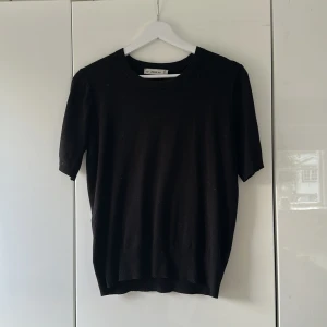 Svart stickad kort armad tröja  från ZARA - Säljer en svart stickad topp från ZARA med rund halsringning och korta ärmar. Enkel och stilren design som passar perfekt till många olika outfits. Mjuk och skön kvalitet.
