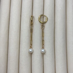 Guldiga örhängen med kedja och pärla - Trendiga guldiga örhängen med lång kedja och vit pärldetalj längst ner. Örhängena har en modern design med olika ringar och länkar, vilket ger en cool och stilren look.