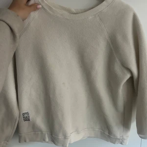 Beige sweatshirt från Beach House - Säljer en enkel och stilren beige sweatshirt från Beach House. Tröjan har rund halsringning, långa ärmar och en liten logotyp nertill. Perfekt för en avslappnad look.