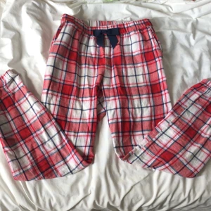 Pyjamas byxor - Säljer ett par mjuka och sköna mjukisbyxor från Kappahl i rödvitrutigt mönster. Byxorna har resår i midjan och ett blått knytband framtill. Perfekta för att chilla hemma eller som pyjamasbyxor.