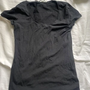 Svart t-shirt med rund hals från H&M - En enkel svart t-shirt från H&M med rundad halsringning och korta ärmar. Perfekt basplagg att ha i garderoben och lätt att matcha med olika outfits.