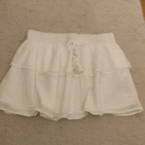 Vit volangkjol  - Vit volang kjol ifrån Gina Tricot i storlek 158/164 men passar mig som har XS/S. Den är endast använd 1 gång, går att justera midjan med banden💗