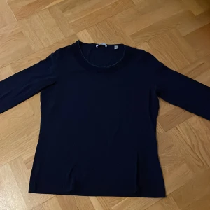 Mörkblå långärmad tröja från Peter HahnHahn - Säljer en stilren mörkblå trekvartsärmad tröja från Peter Hahn. Tröjan har en klassisk rund halsringning med spets kant och är tillverkad i ett mjukt material som passar perfekt till många olika outfits.