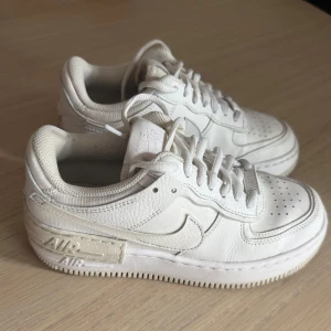 Nike Air Force 1 shadow  - Säljer ett par klassiska vita Nike Air Force 1 shadow. Lite blå färg är kvar från när det var trendigt att måla swooshen men går att tvätta bort med sprit!
