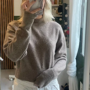 Beige stickad tröja från & Other Stories - Mysig beige stickad tröja från & Other Stories med hög hals och en croppad passform. Lite nopprig.