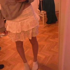 Vit volangkjol med broderade detaljer - Superfin vit kjol med volanger och broderade blommor. Kjolen har dragkedja i sidan och är kort i modellen. Perfekt för sommarens alla tillfällen och ger en söt och fräsch look. Vet inte vilket märke eftersom lappen är borta. Skriv om du har frågor❤️