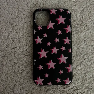 Svart mobilskal med rosa stjärnor - Säljer ett svart mobilskal med rosa och vita stjärnor i strl iPhone 11. Skalet är gjort av plast och har öppning för kamera. Passar till en smartphone med större kameralins! 💗