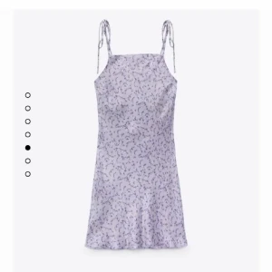 Ljuslila blommig kortklänning med knytband storlek S - Superfin ljuslila klänning i sidentyg med små blommor och smala axelband som knyts. Klänningen har en rak passform och är kort, perfekt för varma dagar. Fin i skick!