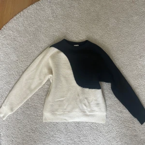 Stickad tröja - Säljer denna stickade tröja i nyskick. Tröjan har ett coolt blockmönster med svart på ena sidan och vit på den andra, samt rund halsringning och långa ärmar💗