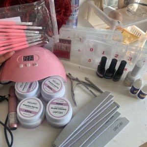 Nagelkit med rosa gel och tillbehör - Komplett nagelkit med rosa gel, flera nagelborstar med rosa skaft, nagelfilar, nageltippar i olika storlekar, nagellim, UV-lampa och verktyg. Perfekt för att skapa snygga naglar hemma. Innehåller även primer- och topplack.