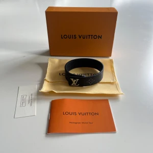 Louis Vuitton Armband - Snyggt svart armband från Louis Vuitton Monogram World Tour med klassisk LV-logga i silver på framsidan. Armbandet är gjort i exklusivt skinn med diskret monogrammönster och har en stilren, modern look. Självklart autentiskt och allt og fås med vid köp. Hör av dig vid funderingar.// Ville