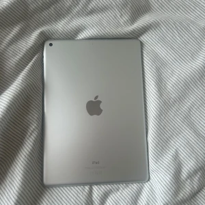 Ipad nionde generationen - 64GB kapacitet. Silverfärgad. Ipaden är gammal och använd men fungerar endå som den ska. Den är lite långsam men är lämplig till priset. Kommer nollställd utan laddare. Ipadskal ingår