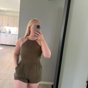 Olivgröna jumpsuit - Olivgrön jumpsuit med hög krage, knyte i nacken och öppen rygg. Från h&m i storlek 36