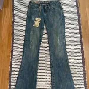 Blå bootcut jeans från Cross Jeans - Supersnygga lågmidjade bootcut jeans från cross jeans. För långa för mig så måste tyvärr sälja. Snygg wash och coola detaljer, i mycket bra skick!  Midjemått: ca 33cm (mätt platt)  Innerbenslängd: ca 85cm (mätt platt)  Grenhöjd: ca 17 cm (mätt platt)