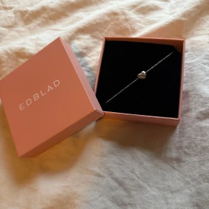 Silverarmband med hjärta från Edblad - Superfint och stilrent armband från Edblad i silverfärg med ett litet hjärta i mitten. Tunn kedja och diskret design som passar perfekt till din vardagsstil. Levereras i original ask med Edblad-logga. Perfekt present till någon du gillar!