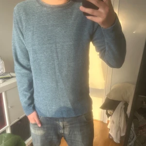 Blå stickad tröja från Norse Projects - Säljer en stilren blå stickad tröja från Norse Projects. Tröjan har en klassisk rund halsringning och lång ärm. Materialet är mjukt och passar perfekt till jeans. Enkel och snygg design som funkar året runt.
