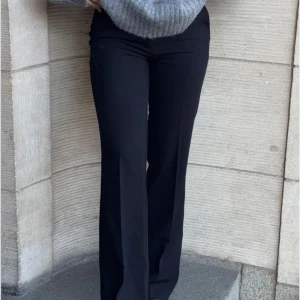 Svarta bootcut kostymbyxor Nelly  - Snygga svarta kostymbyxor med bootcut passform och low midja. Byxorna har en klassisk look med raka ben som blir vidare nedtill. Perfekta att styla med en stickad tröja eller skjorta för en clean vibe. Knappt använda 