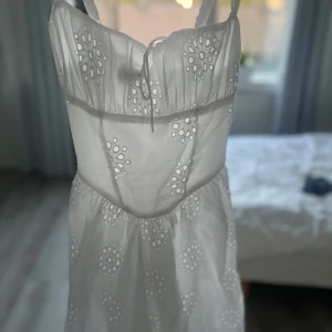 Vit kortklänning med snörning Gina Tricot - Supersöt vit kortklänning från Gina Tricot i storlek 34. Klänningen har broderade blommor, smala axelband och snygg snörning i ryggen. Använd en gång i någon timme sedan dess aldrig mer så den är som ny.