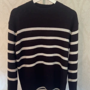 Randig svartvit stickad tröja Divided - Svart stickad tröja från Divided med vita horisontella ränder. Klassisk rund halsringning och långa ärmar. Perfekt för dig som gillar enkel men snygg stil. Mjuk och skön att ha på sig, passar till jeans eller kjol.