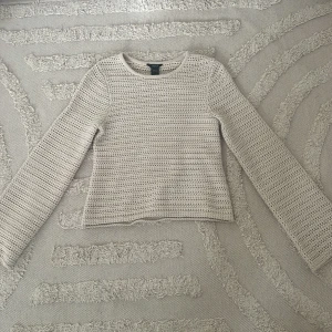 Beige stickad tröja från Lindex - Säljer en beige stickad tröja från Lindex i storlek XS. Tröjan har ett luftigt hålmönster, rund hals och långa ärmar med lite vidare passform. 