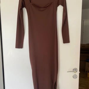 Brun långärmad långklänning NLY Trend - Säljer en snygg brun långklänning från Nelly i storlek XS. Klänningen har lång ärm, figurnära passform och en slits på sidan. Använd någon enstaka gång, inga tecken på användning.