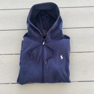 Ralph lauren zip hoodie | S - Hej! Säljer nu en marinblå Ralph lauren tröja i bra skick, de är storlek S på den. Passar perfekt för både avslappnad vardagsstil och en mer uppklädd casual look. Hör gärna av er om ni har några frågor🤩 MVH VONUE