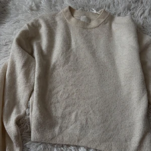 Vit stickad tröja från H&M - Mysig  vit stickad tröja från H&M i storlek S. Tröjan har rund halsringning, ribbade muddar och är långärmad. Perfekt för lager-på-lager och enkel att matcha med jeans eller kjol. Stilren och basic design som funkar året runt.