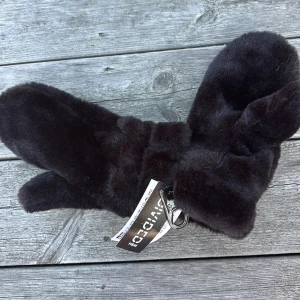 Svarta pälsvantar från H&M Divided - Helt nya, prislapp kvar. Mysiga svarta vantar från H&M Divided i fluffig fuskpäls. Perfekta för kalla dagar när du vill hålla händerna varma och samtidigt se stilren ut. Vantarna har en enkel design och känns riktigt mjuka och sköna.