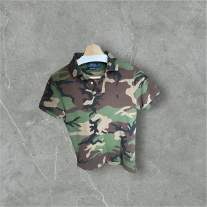 Camouflage pikétröja från Polo Ralph Lauren - Stilren Polo Ralph Lauren pikétröja i camouflage-mönster. Klassisk passform med krage och knappslå framtill. Diskret broderad logga på bröstet. Perfekt för en avslappnad men trendig look.  ✔ Storlek: (S) ✔ Färg: Camouflage (grön/brun/svart) ✔ Märke: Polo Ralph Lauren ✔ Skick: (Bra skick inga hål och sånt)
