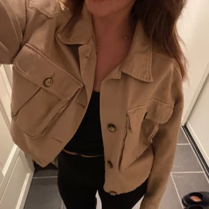 Beige croppad jeansjacka  - Säljer min superfina trenchcoat liknande jeansjacka ifrån Gina tricot, som just nu trendar, den är i gott skick!
