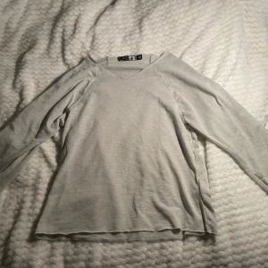 Ljusgrå tröja med knyt från Artist Girls - Supersöt ljusgrå långärmad tröja från Artist Girls i 100% polyester. Tröjan har snygga knyt-detaljer på ärmarna som ger en extra touch. Perfekt för dig som gillar stilrena och enkla plagg med en twist. Lite nopprig men går att ta bort enkelt 💕💕