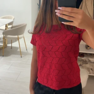 Röd blus från Jacqueline de Yong XS - Säljer en röd blus från Jacqueline de Yong i storlek XS. Toppen har korta ärmar och ett snyggt hålmönster i geometrisk stil. Perfekt att styla med jeans eller kjol för en trendig look.