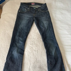 Levi's 513 mörkblå jeans 27/34 - Säljer ett par Levi's 513 jeans i mörkblå tvätt med snygga slitningar och kontrastsömmar. Klassisk femficksmodell med raka ben och normal passform. Perfekta till sneakers eller boots, och har coola detaljer på bakfickorna.