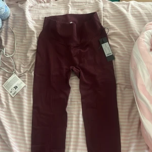 Vinröda leggings från lager157 - Snygga vinröda leggings från Lager 157 med hög midja och tight passform. Perfekta för träning eller chill, med mjukt och stretchigt material som sitter skönt mot kroppen. Stilren design utan mönster och med bred linning för extra support.