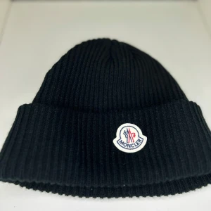 Svart ribbad mössa från Moncler - Svart ribbstickad mössa från Moncler, använd fåtal gånger  