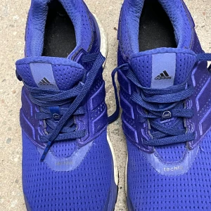 Blå adidas techfit sneakers strl 39 1/3 - Snygga blå adidas sneakers med techfit-överdel och coola detaljer. Skorna har snörning, ventilerande mesh och en sula med svarta och röda inslag. Perfekta för dig som gillar sportig stil och vill ha bekväma skor till vardagen.