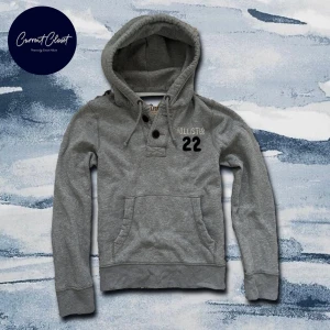 Grå hoodie från Hollister med knappar - Snygg grå hoodie från Hollister med broderad logga och siffran 22 på bröstet | Size M och passar true to size | Vintage och slitningar förekommer