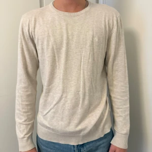 Beige stickad tröja från Lindbergh - Säljer en stilren beige stickad tröja från Lindbergh White i storlek L. Tröjan har rund halsringning, lång ärm och är tillverkad i ett mjukt material som passar perfekt till jeans. Enkel och clean look som funkar året runt.