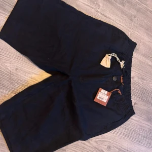Mörkblå shorts från Loro Piana, storlek 34 - Snygga mörkblå shorts från Loro Piana i storlek 34. De har elastisk midja med dragsko och knapp, samt bakficka med knapp och diskret logga. Tillverkade i ett mjukt och lyxigt material, perfekta för varma dagar.