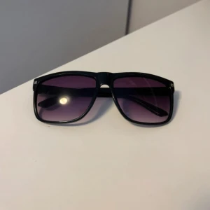 Svarta solglasögon - Ett par schyssta solglasögon med svart båge och blå/lila tonad glas. Riktigt stilrena och funkar till varje tillfälle, pris är förhandlingsbart.