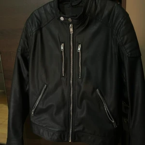 Svart skinnjacka  - Säljer en svart skinnjacka med coola detaljer som du kan ha på dig nu i höst den är nästan oanvänd i väldigt fin skick 