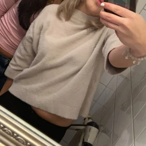 Beige croppad stickad tröja - Supermjuk och croppad beige stickad tröja med trekvartsärm. Perfekt för dig som gillar en avslappnad och trendig look. Enkel att matcha med både jeans och kjol. Snygg och stilren design som passar året runt.