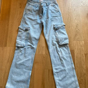 Ljusblå cargo jeans från Perfect Jeans - Säljer ett par ljusblå cargo jeans från Perfect Jeans i storlek 32. Byxorna har raka ben, stora cargofickor på sidorna och klassiska bakfickor med låg midja 
