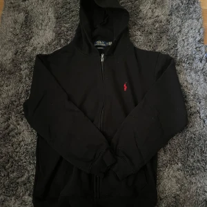 Ralph Lauren Zip Hoodie - Säljer nu en ritkigt snygg Ralph Lauren zip Hoodie. Hoodien är i nyskick utan tecken på användning, står storlek M men sitter som S därav varför jag säljer den. Tveka inte att höra av er angående frågor eller prissänkning!