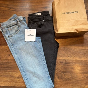 J.Lindeberg jeans i svart och ljusblå - Två par snygga jeans från J.Lindeberg, ett par i klassiskt svart och ett par i ljusblå tvätt. Båda har femficksdesign, diskret JL-logo på myntfickan och är tillverkade i mjuk bomullsdenim med stretch. Perfekta för en clean och modern look. Modell Jay i storlek 31 midja 32 längd .Endast provade och säljs pga av fel storlek.Pris 500:- st