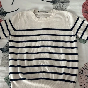 Randig vit tröja från Zara - Vit tröja från Zara med marinblå horisontella ränder. Modellen har korta ärmar och rund halsringning. Mjuk och skön känsla, perfekt för vår och sommar. Klassisk och stilren look som funkar till många outfits. Priset kan även diskuteras 