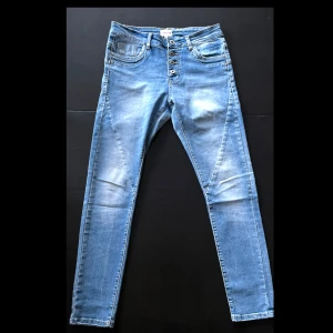 Ljusblå skinny jeans Chica London XS - Snygga ljusblå skinny jeans från Chica London med flera knappar framtill och cool stjärndetalj på bakfickan. Jeansen har klassisk femficksdesign och är tillverkade i stretchigt denim för en tight passform.